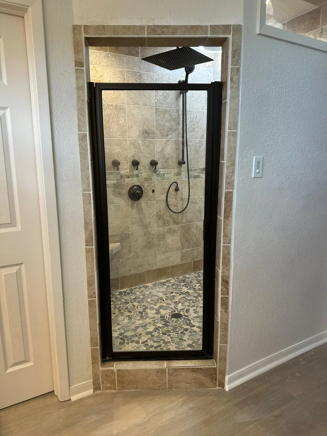 Custom shower framed in matte black, tiled floor to ceiling.