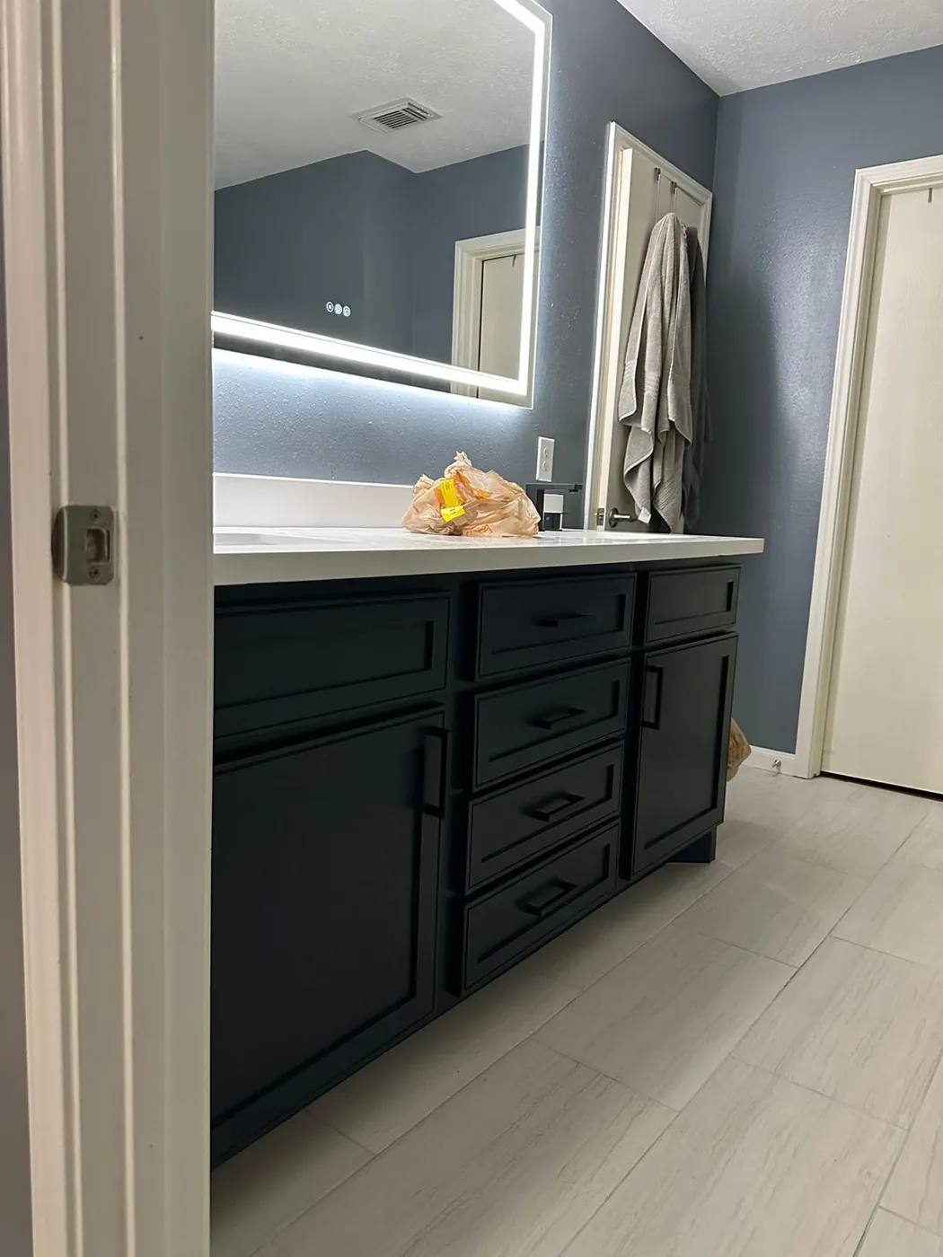 Navy vanity under a backlit LED mirror.