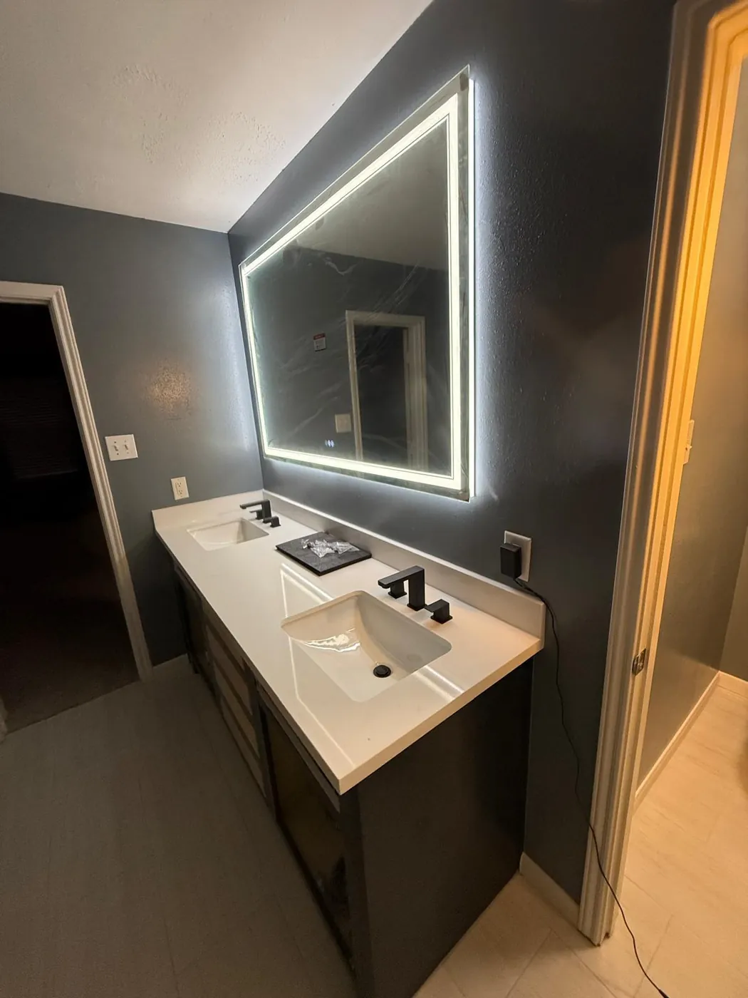 After: the same double vanity finished with counters, sinks and the LED mirror.