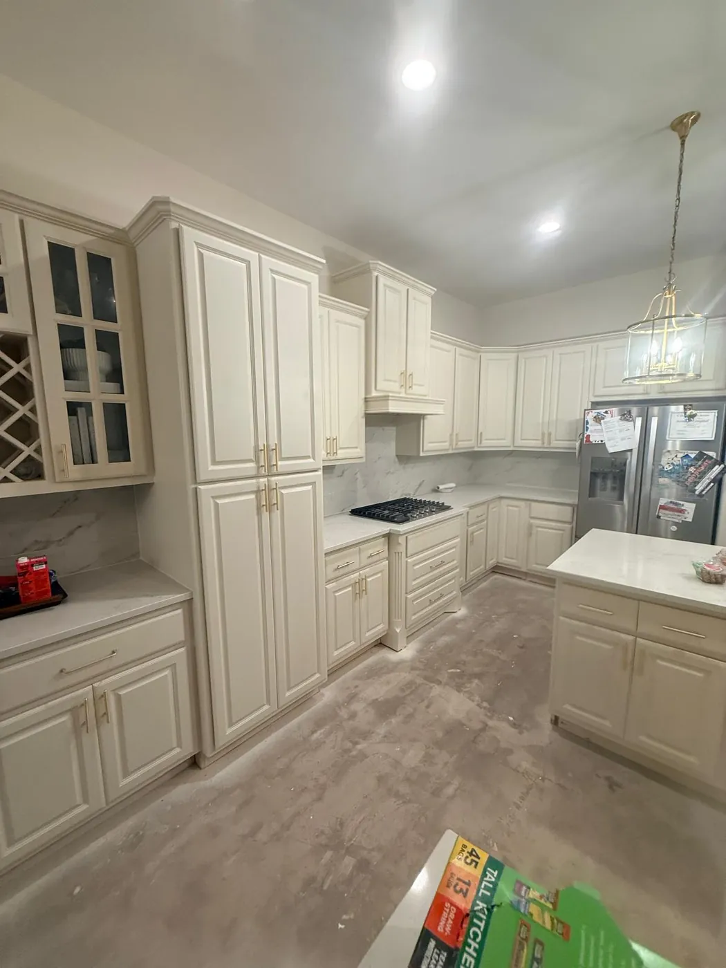 White kitchen with a custom island and glass-front cabinets, ready for counters.