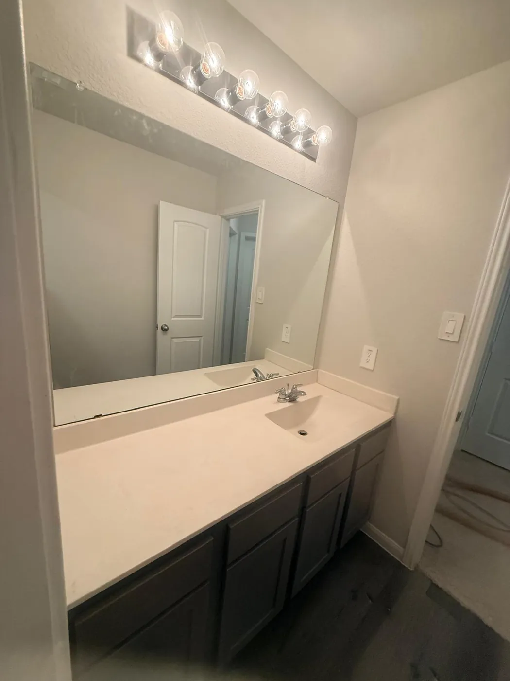 Long vanity with a seamless white counter and new lighting.